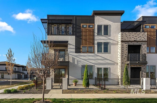modern home featuring stucco siding, brick siding, and a balcony