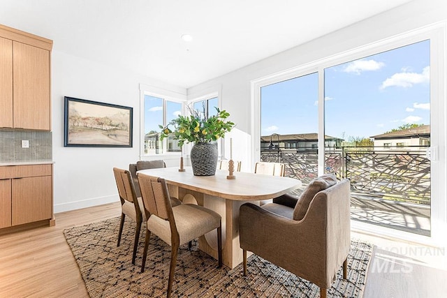dining room featuring light wood-style flooring, healthy amount of natural light, and baseboards
