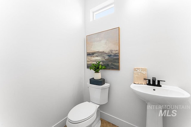 half bathroom featuring baseboards and toilet