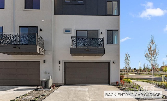 view of building exterior with a garage, cooling unit, and driveway