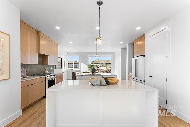 kitchen with gas stove, a center island, high quality fridge, light wood-style floors, and recessed lighting