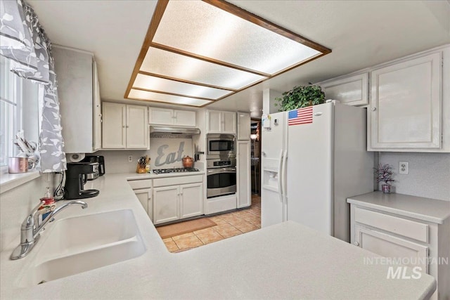 kitchen featuring a sink, light countertops, stainless steel appliances, and under cabinet range hood