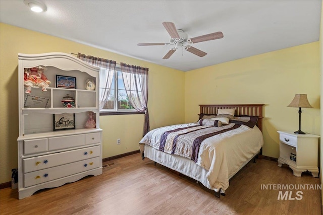 bedroom with baseboards, ceiling fan, and wood finished floors