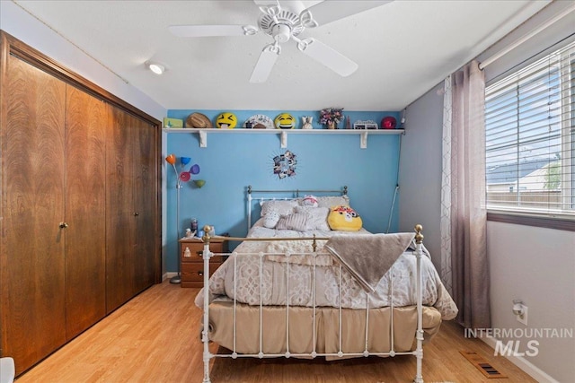 bedroom featuring a closet, baseboards, ceiling fan, and wood finished floors