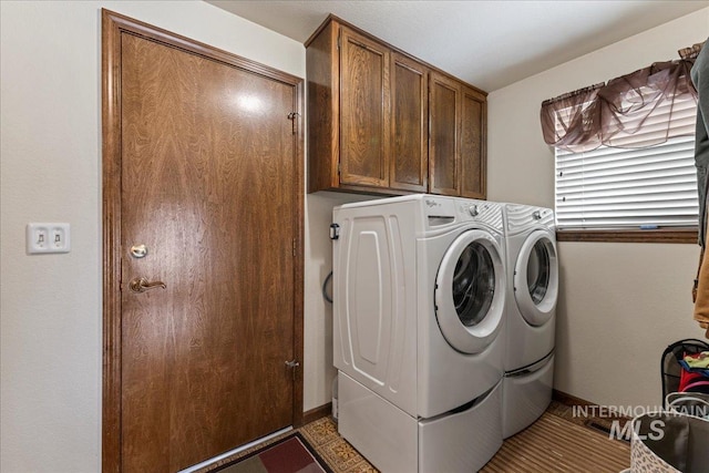 clothes washing area featuring cabinet space, baseboards, and washer and dryer