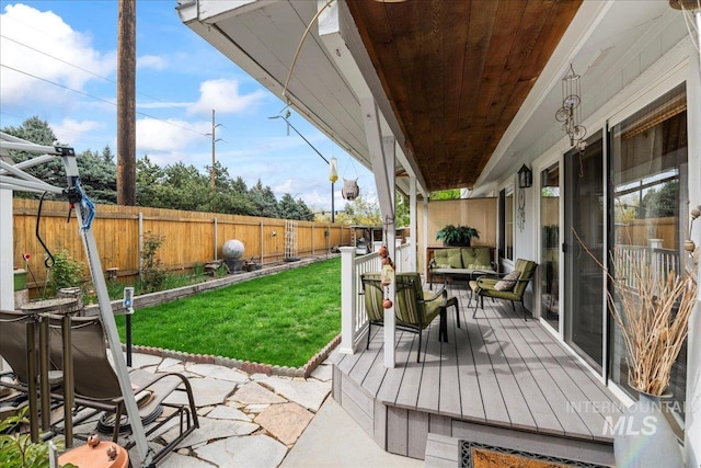 wooden deck featuring a lawn, a fenced backyard, and a patio