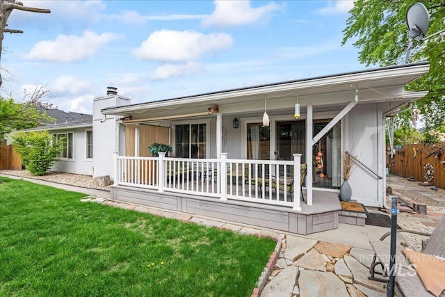 back of property with a porch, a yard, fence, and a chimney