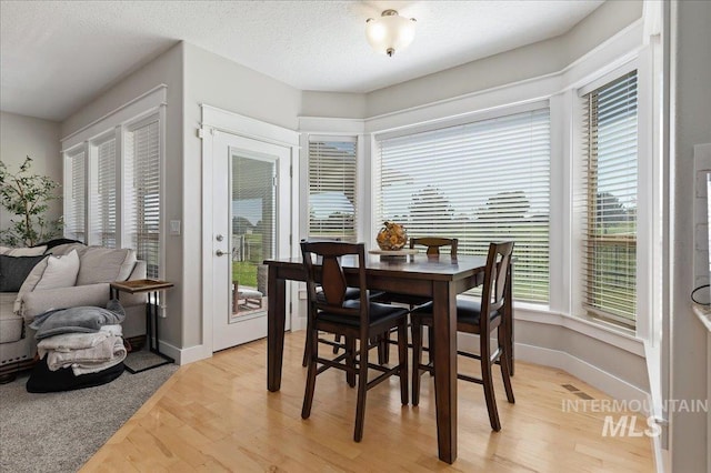 dining space with light hardwood / wood-style flooring and a textured ceiling