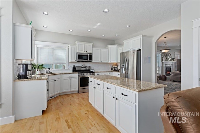 kitchen with a center island, backsplash, sink, appliances with stainless steel finishes, and white cabinetry