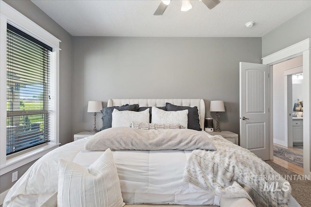 bedroom with ceiling fan, a textured ceiling, and multiple windows