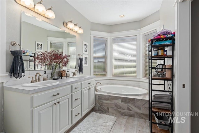 bathroom featuring hardwood / wood-style floors, vanity, and tiled bath