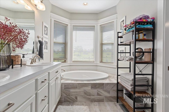 bathroom featuring tiled tub and vanity