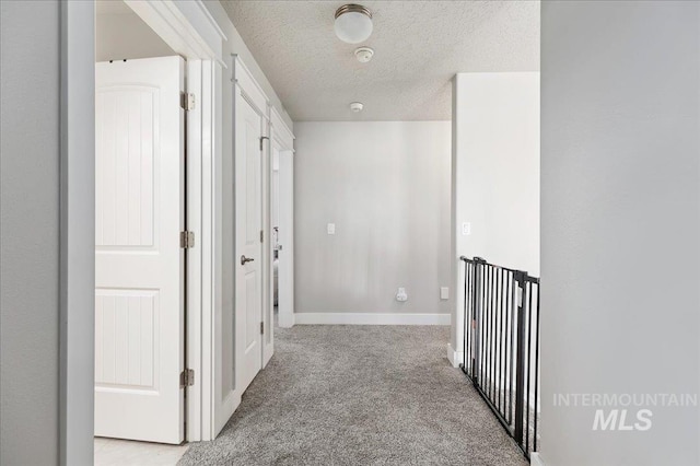 corridor featuring a textured ceiling and light carpet