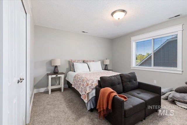 bedroom with light colored carpet and a textured ceiling