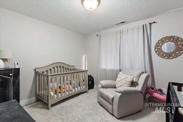 carpeted bedroom featuring a crib and a textured ceiling