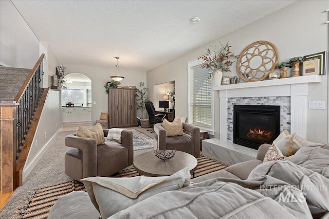 living room featuring a tile fireplace, light carpet, and a textured ceiling