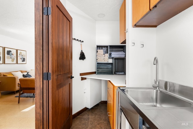 2036 N Blaine Way, Boise, ID 83702 - kitchen featuring light countertops, a sink, a textured ceiling, brown cabinets, and baseboards