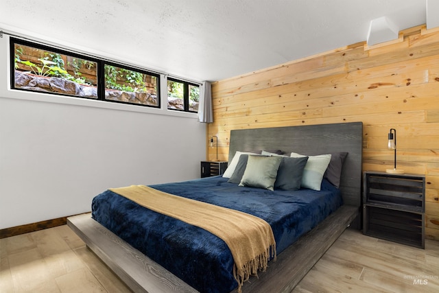 2036 N Blaine Way, Boise, ID 83702 - bedroom featuring wooden walls, light wood finished floors, and a textured ceiling