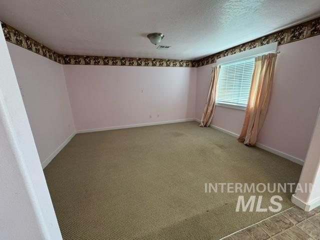 empty room with a textured ceiling and light carpet