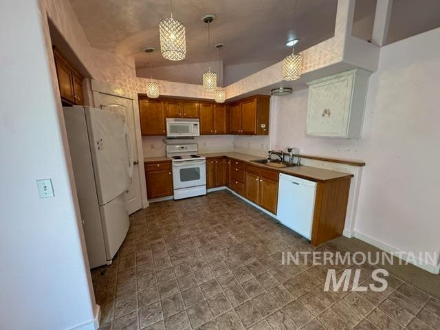 kitchen with pendant lighting, white appliances, and sink