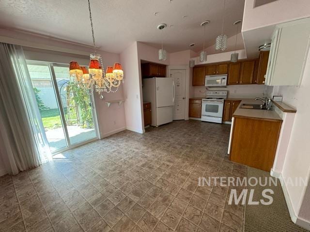 kitchen featuring white appliances, sink, decorative light fixtures, and a notable chandelier