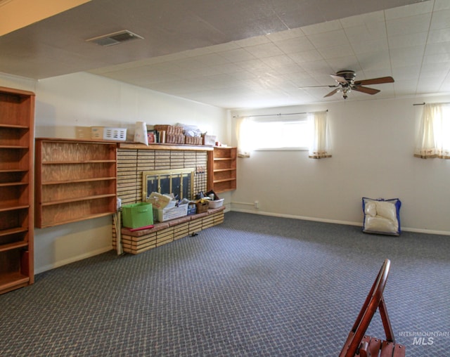 unfurnished room featuring a fireplace, dark carpet, and ceiling fan