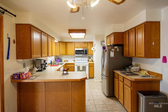 kitchen with sink, light tile patterned floors, kitchen peninsula, ceiling fan, and stainless steel appliances
