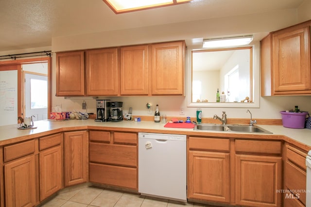 kitchen with light tile patterned flooring, white dishwasher, plenty of natural light, and sink