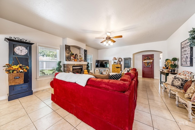 living room with ceiling fan, a fireplace, and light tile patterned flooring