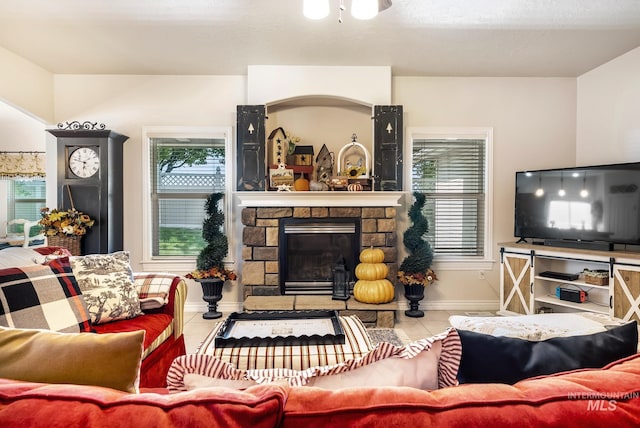 tiled living room featuring a healthy amount of sunlight and a stone fireplace