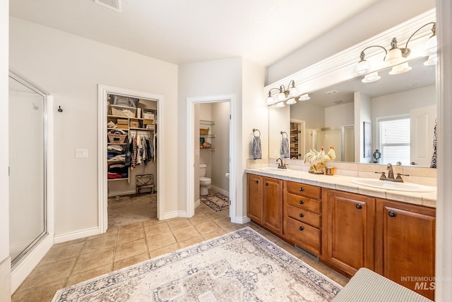 bathroom with tile patterned flooring, vanity, toilet, and a shower with door