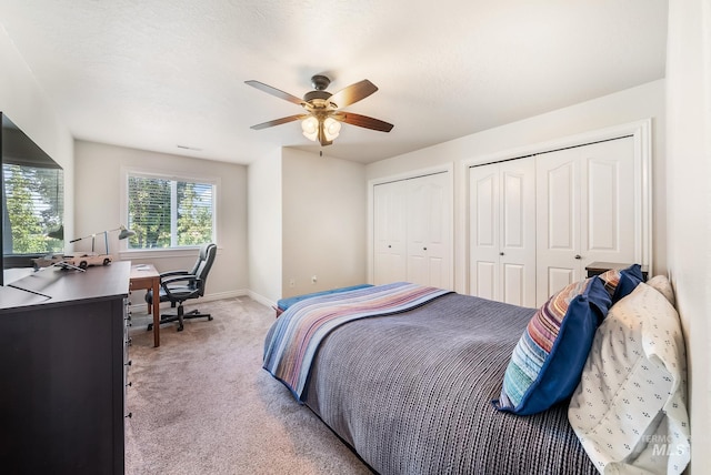 carpeted bedroom featuring ceiling fan and two closets