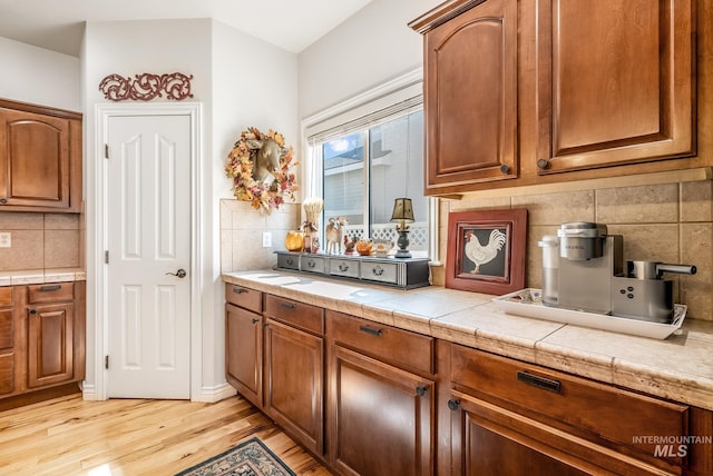 kitchen with backsplash, light hardwood / wood-style floors, and tile counters