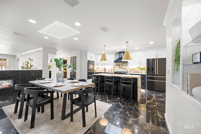 dining room with recessed lighting, a skylight, a multi sided fireplace, marble finish floor, and ornamental molding