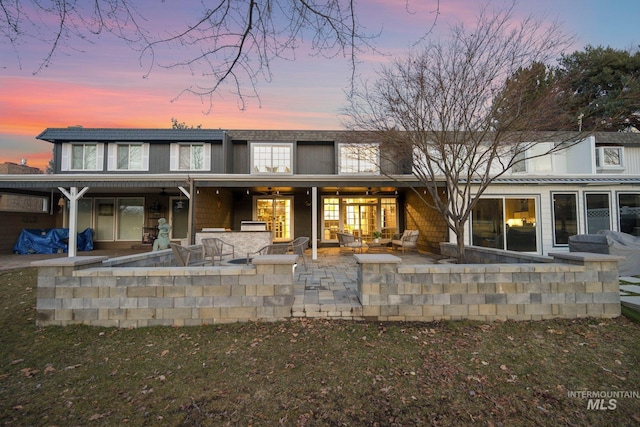 back of property at dusk featuring a patio area and an outdoor living space