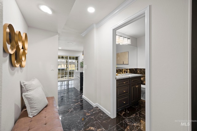 hallway with marble finish floor, recessed lighting, ornamental molding, a sink, and baseboards