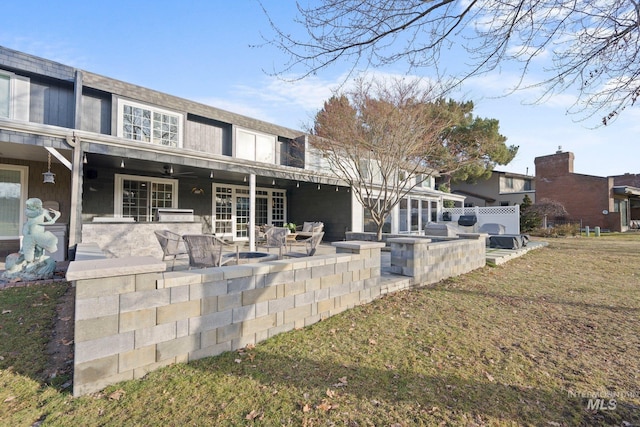 back of house with a patio area, a lawn, and an outdoor kitchen