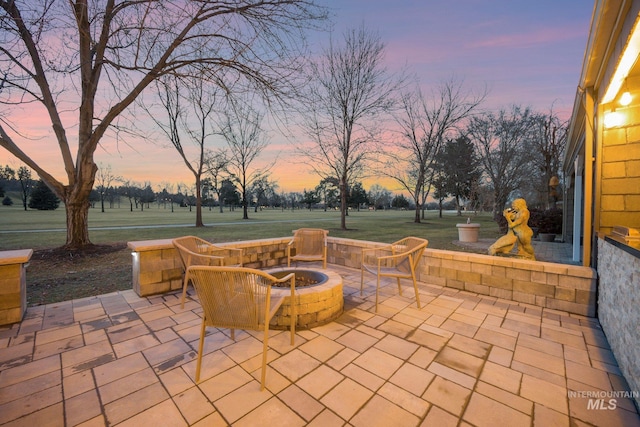 patio terrace at dusk featuring an outdoor fire pit and a yard