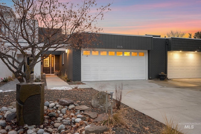 view of front of property featuring a garage, brick siding, and driveway