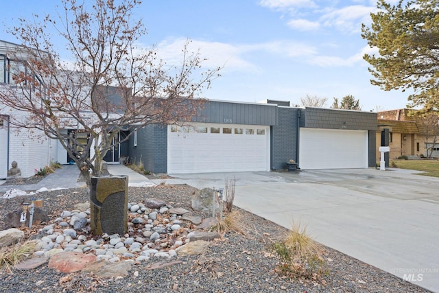 view of front of property featuring a garage, driveway, mansard roof, and brick siding