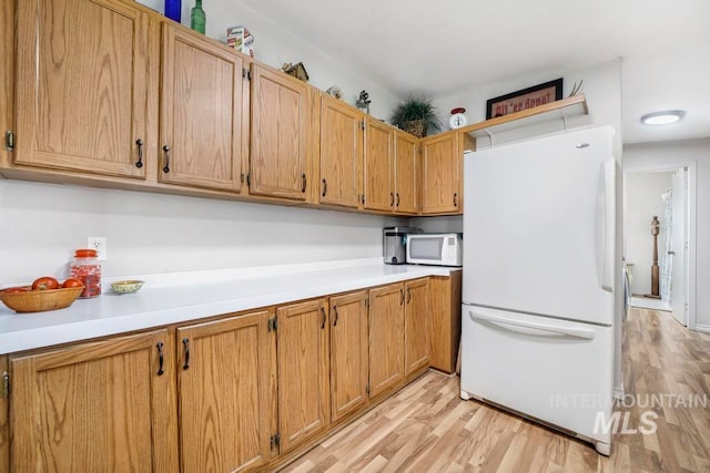 kitchen with white appliances and light hardwood / wood-style flooring