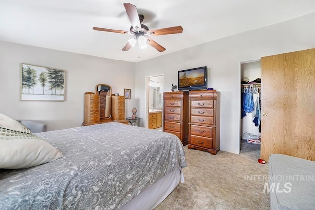 bedroom featuring a closet, light carpet, ceiling fan, and connected bathroom