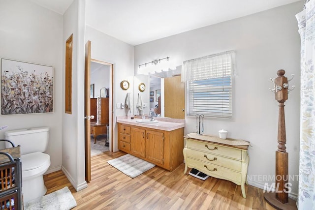 bathroom with toilet, vanity, and hardwood / wood-style floors