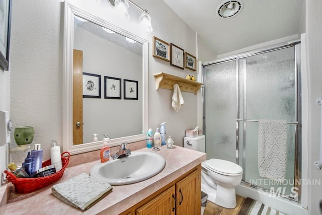 bathroom featuring hardwood / wood-style floors, oversized vanity, toilet, and walk in shower