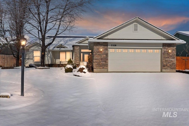 view of front of home with a garage, stone siding, and fence