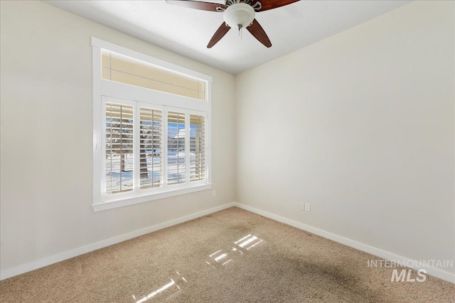 carpeted spare room with baseboards and a ceiling fan