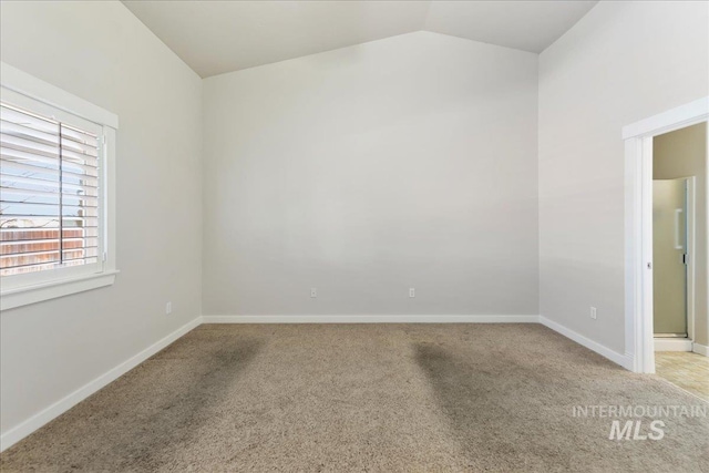 carpeted empty room with lofted ceiling and baseboards