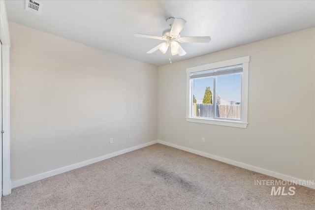 unfurnished room with carpet, visible vents, ceiling fan, and baseboards