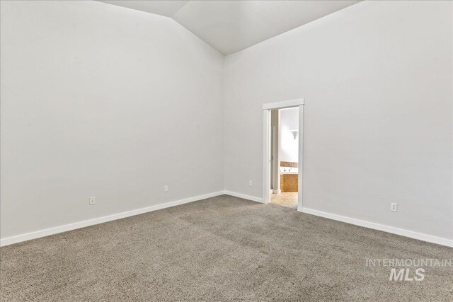 carpeted spare room with lofted ceiling and baseboards