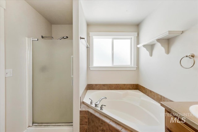 bathroom with a stall shower, a garden tub, and vanity